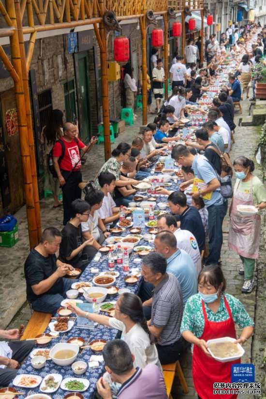 7月29日，在重庆市綦江区安稳镇，人们在“苗家伏羊节”上吃长桌宴。新华社记者 唐奕 摄