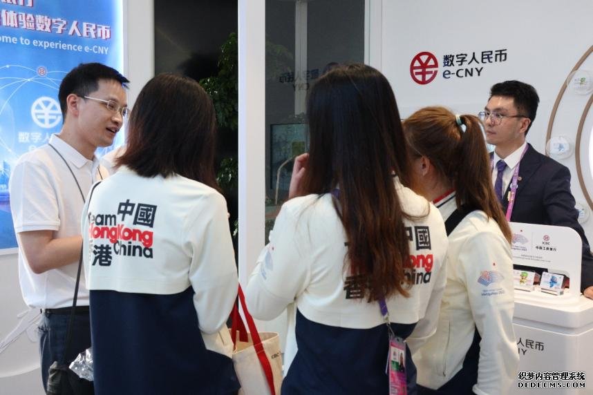 亚运村网点工作人员向中国香港代表团成员讲解充值流程，协助他们体验便捷的数字人民币。 受访者供图