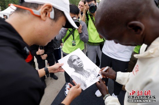 10月13日，基普乔格在朝阳公园为跑友给他画的肖像画签名。<a target='_blank' href='http://ent.people.com.cn/'><p