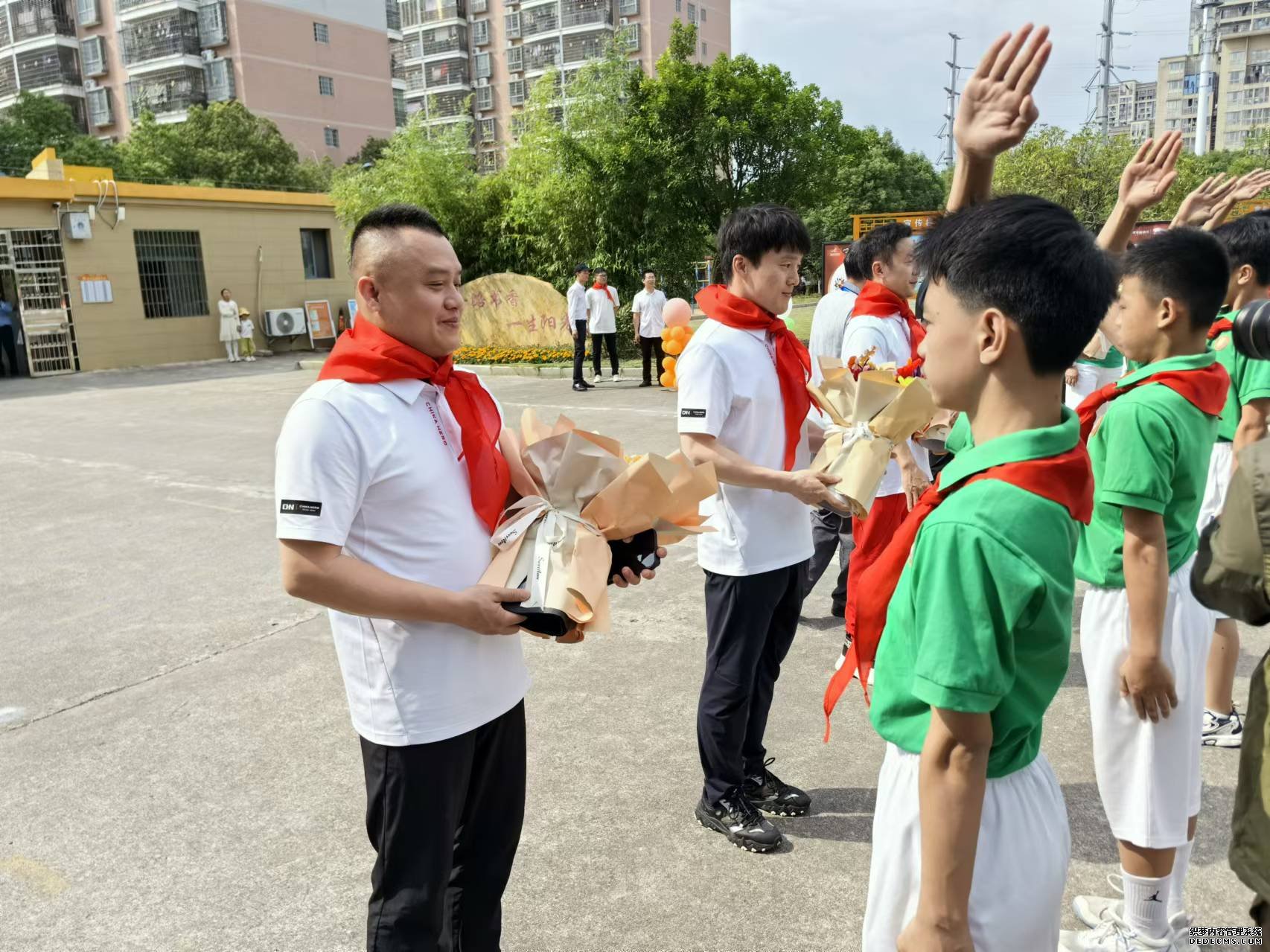 瑞金金穗学校学生为彭勃（左一）等奥运冠军佩戴红领巾、赠送鲜花。人民网记者 杨磊摄